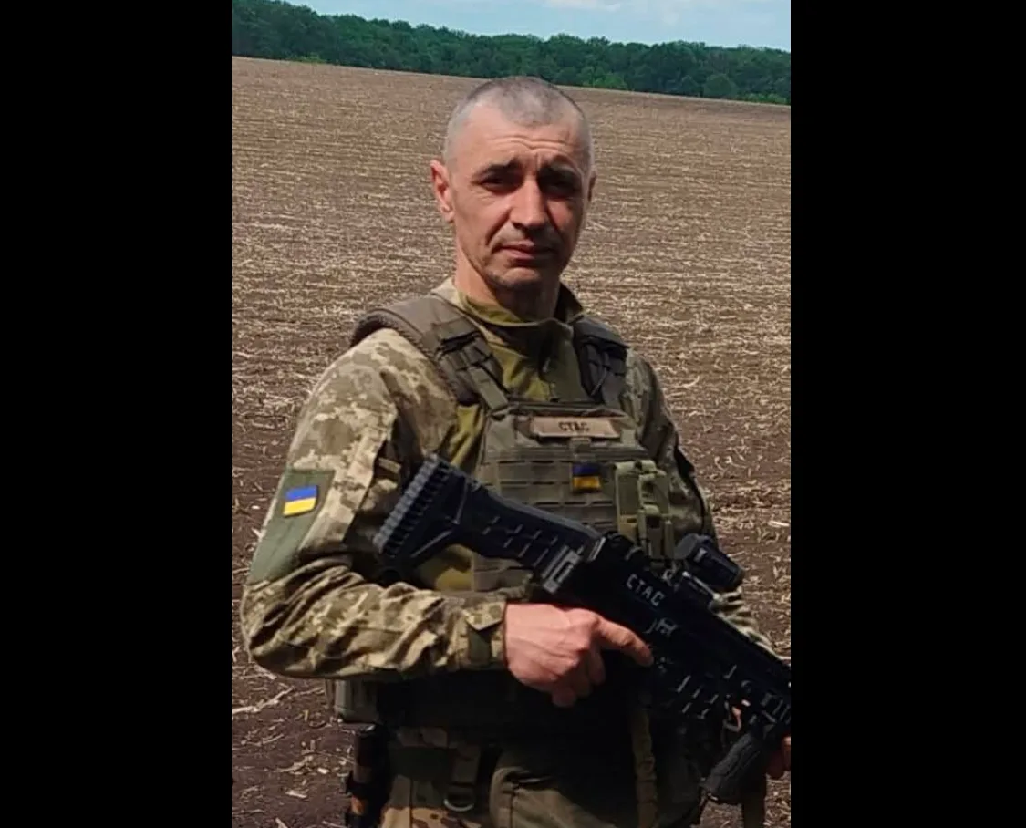 Український військовий з автоматом на тлі поля