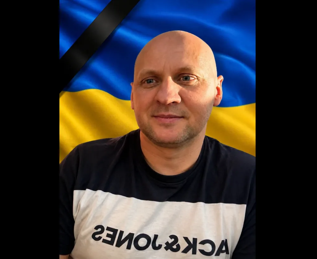 Чоловік на тлі прапора України з чорною жалобною стрічкою
