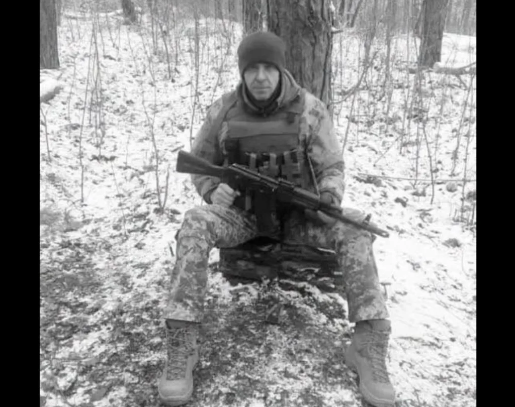 Військовий із гвинтівкою сидить у засніженому лісі