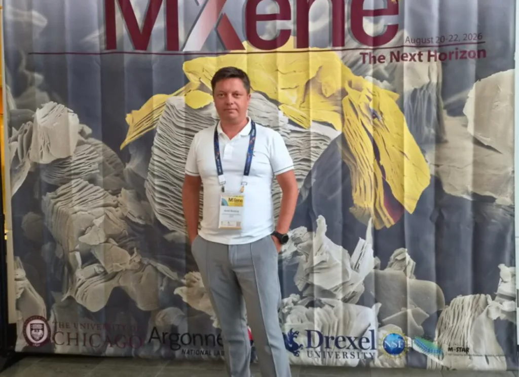 Чоловік на тлі банера конференції Mxene