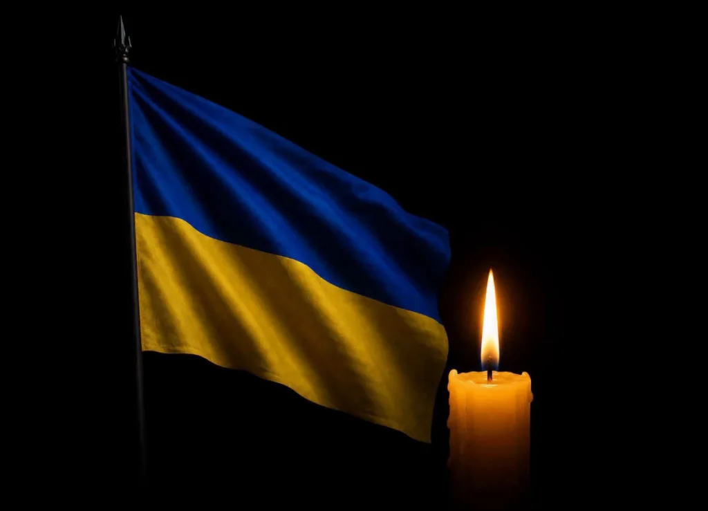 Прапор України поруч із запаленою свічкою
