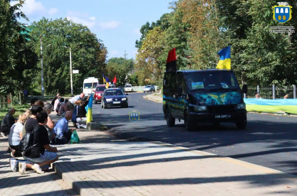 Люди зустрічають авто з українськими прапорами
