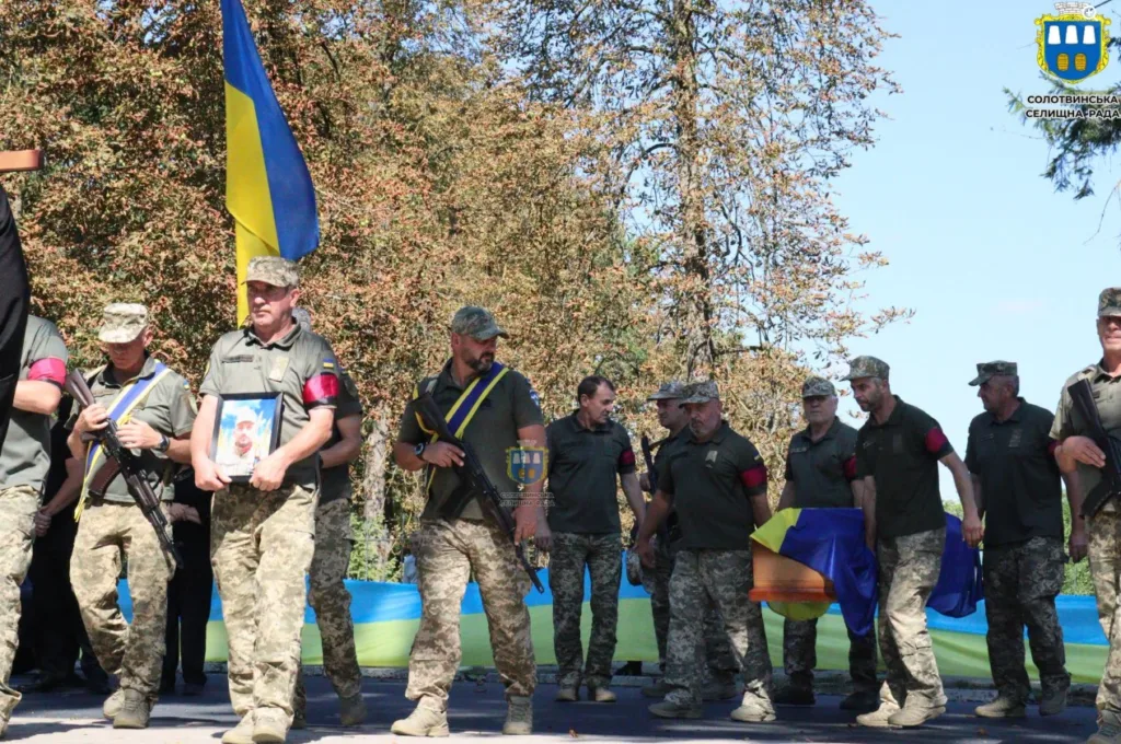 Військові несуть труну, вкриту українським прапором