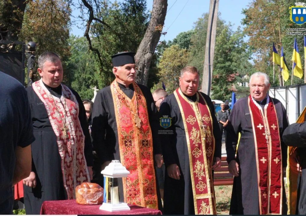 Священники під час церемонії біля українських прапорів