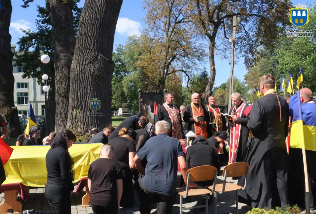 Панахида біля труни, вкритої українським прапором