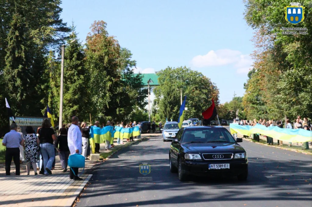 Люди з українськими прапорами зустрічають автомобільну колону