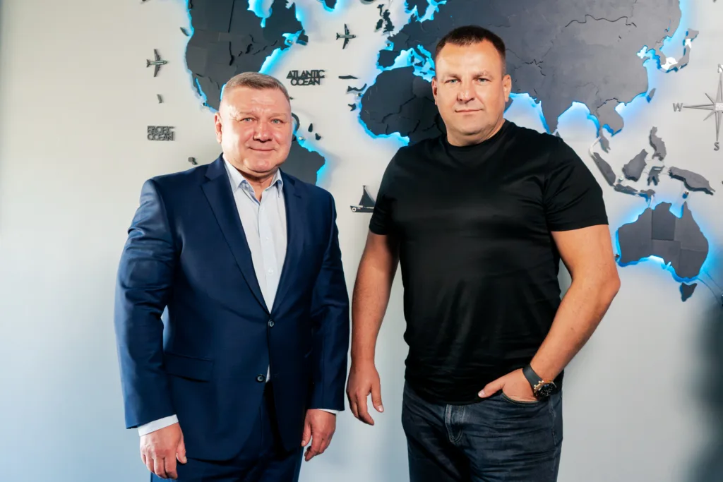 Двоє чоловіків стоять перед підсвіченою картою світу