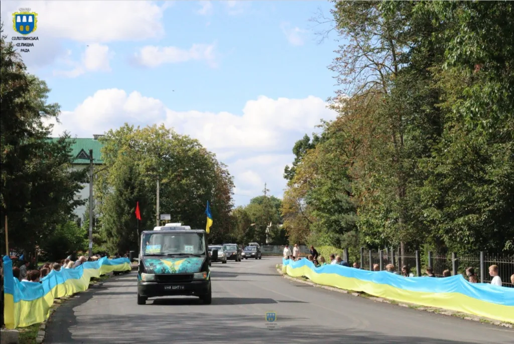 Люди тримають великий український прапор уздовж дороги