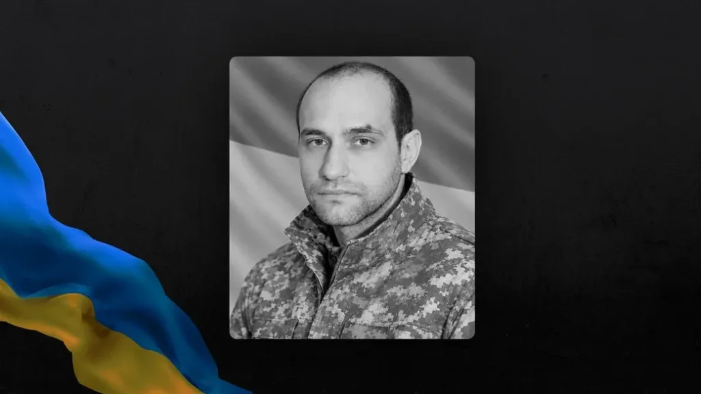 Чорно-білий портрет військового на тлі українського прапора