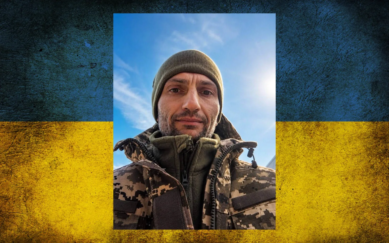 Чоловік у камуфляжі на тлі українського прапора