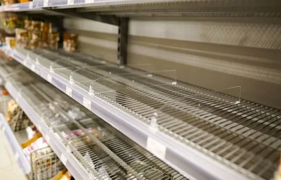 Майже порожні полиці супермаркету з металевими решітками