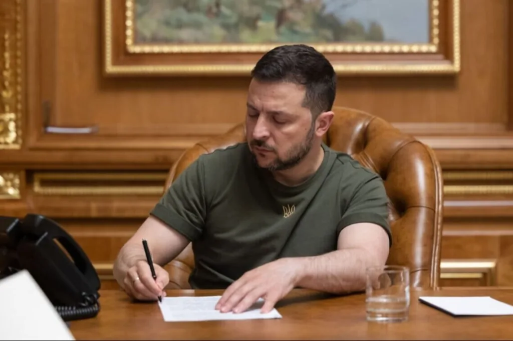 Володимир Зеленський підписує документ за робочим столом