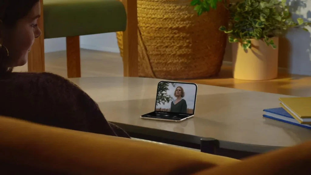 Жінка дивиться відео на складаному смартфоні за столом