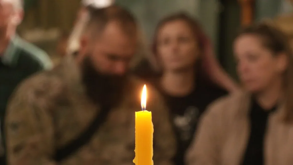 Запалена свічка на тлі людей у розмитому приміщенні