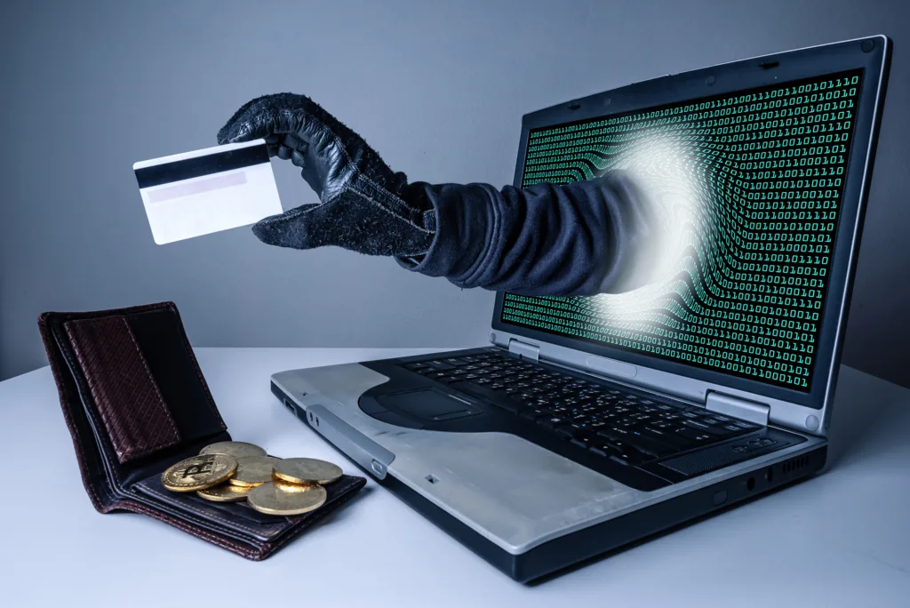 the abstract image of the hacker's hand reach through a laptop screen for stealing credit card in a wallet. the concept of cyber attack, virus, malware, illegally and cyber security.