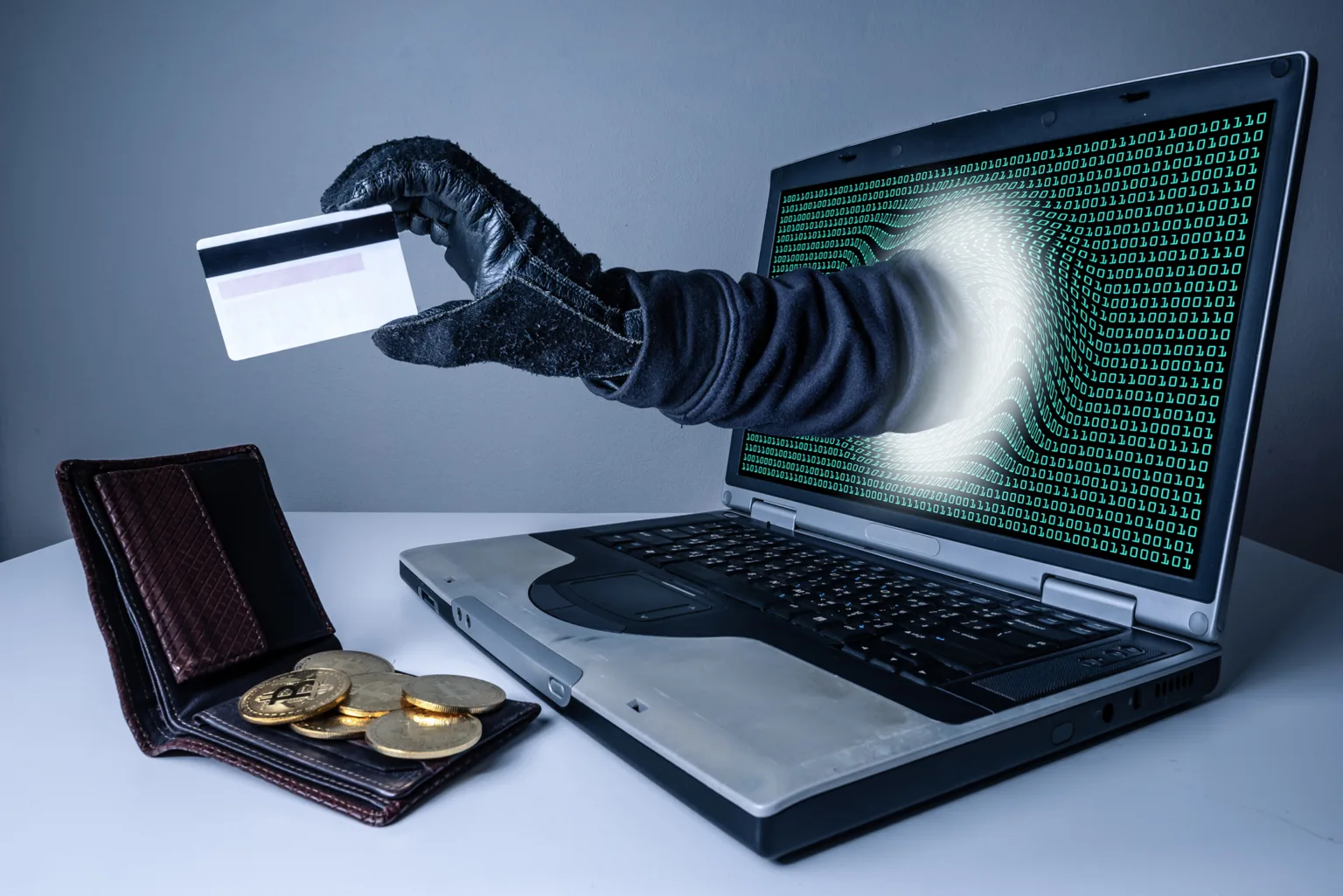 the abstract image of the hacker's hand reach through a laptop screen for stealing credit card in a wallet. the concept of cyber attack, virus, malware, illegally and cyber security.