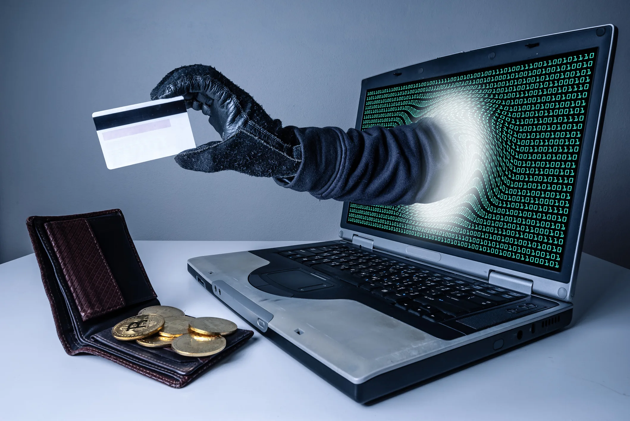 the abstract image of the hacker's hand reach through a laptop screen for stealing credit card in a wallet. the concept of cyber attack, virus, malware, illegally and cyber security.