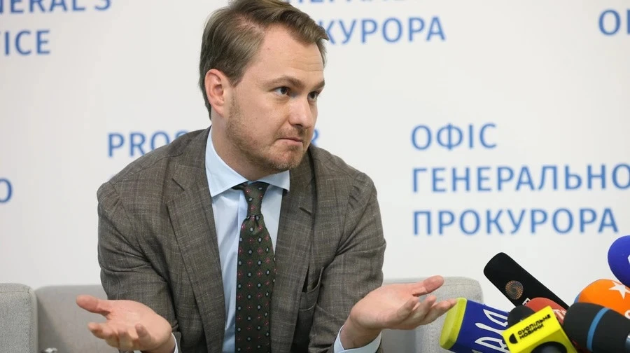 Чоловік у костюмі відповідає на запитання журналістів