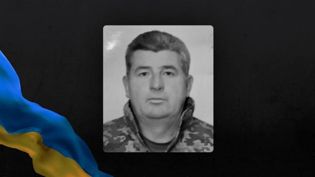 Чорно-білий портрет військового на тлі українського прапора