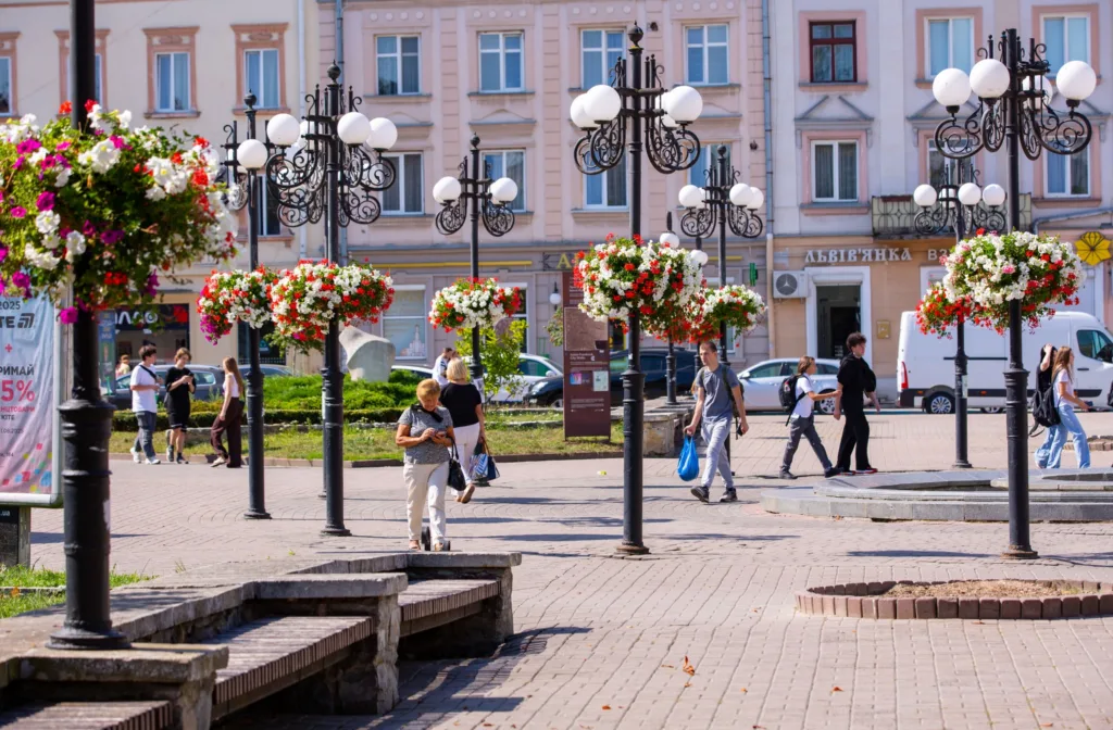 Пішоходи серед ліхтарів із квітковими кошиками