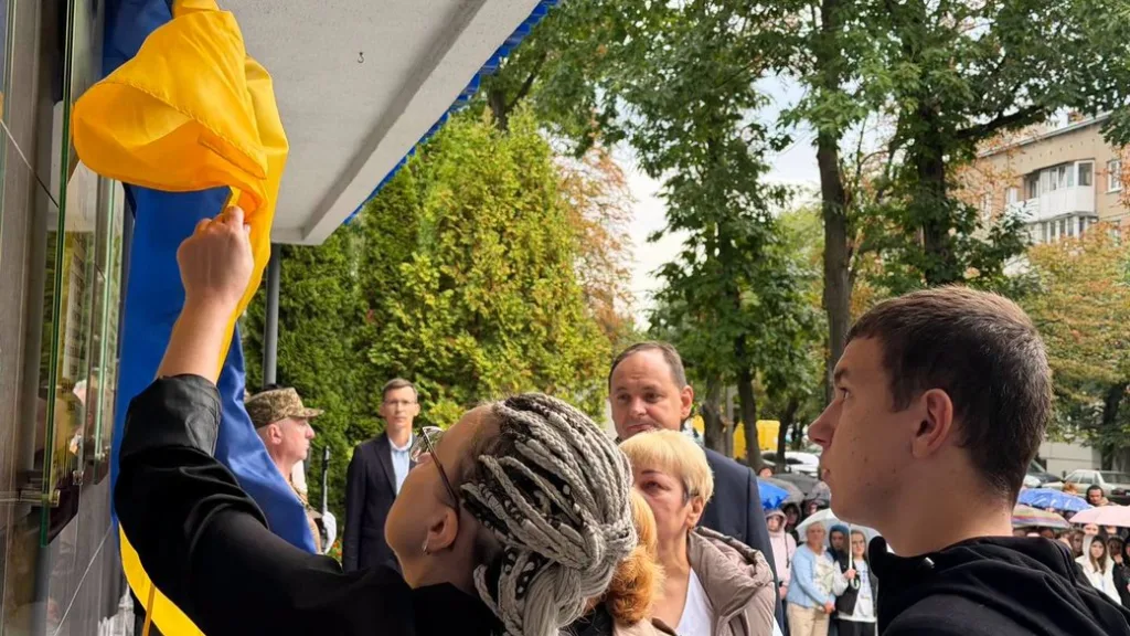 Люди урочисто відкривають український прапор на будівлі