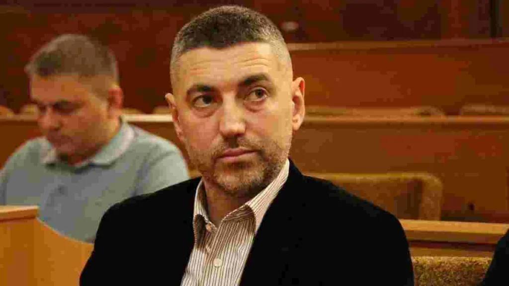 Чоловік у піджаку сидить у залі засідань