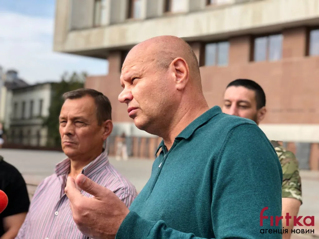 Чоловік виступає перед журналістами біля будівлі