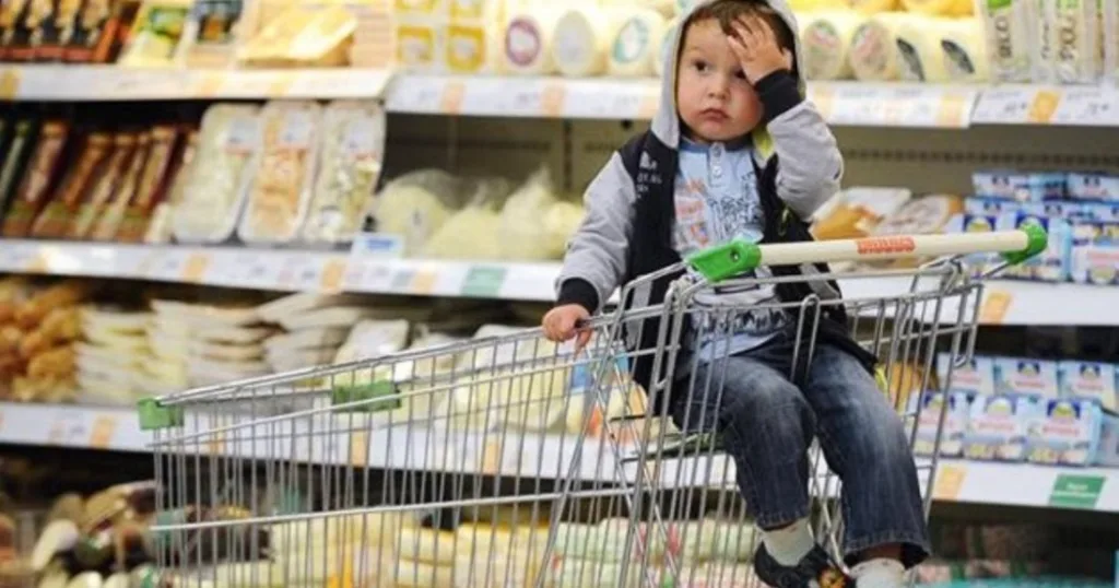 Хлопчик сидить у візку в продуктовому магазині