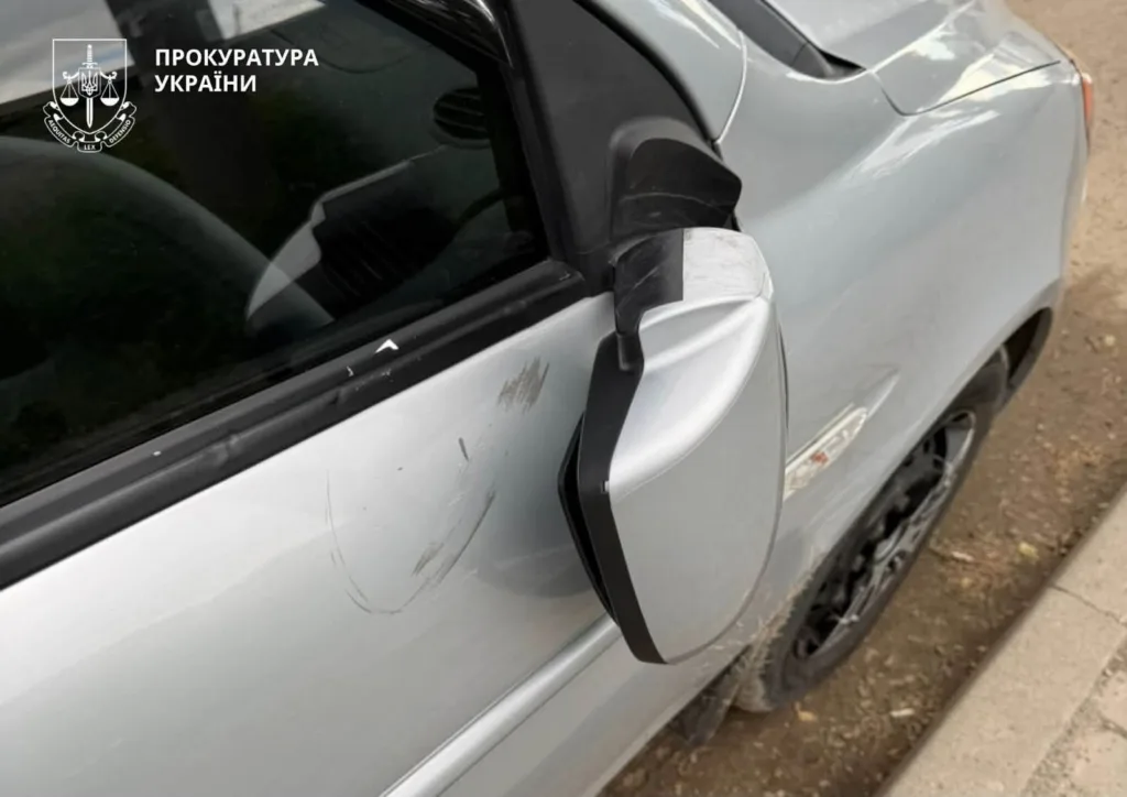 Пошкоджене дзеркало сріблястого автомобіля, закріплене чорною стрічкою
