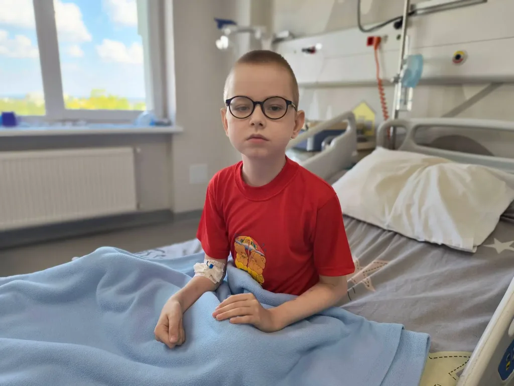 Хлопчик в окулярах сидить на лікарняному ліжку