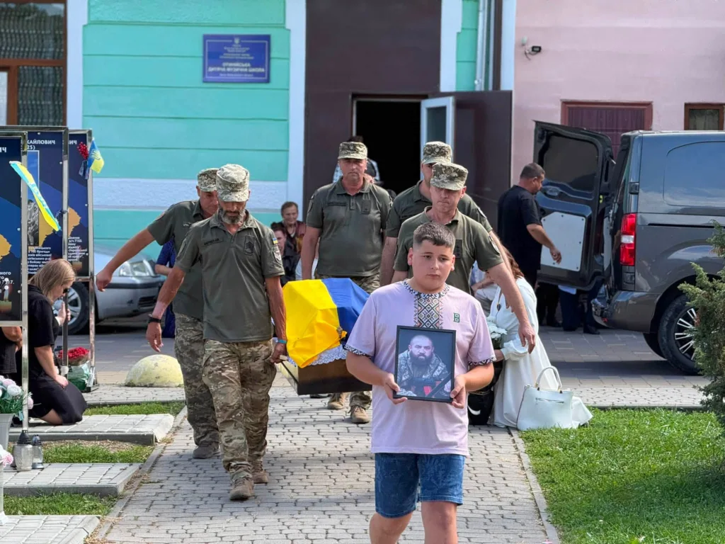 Хлопчик несе портрет загиблого воїна під час похорону