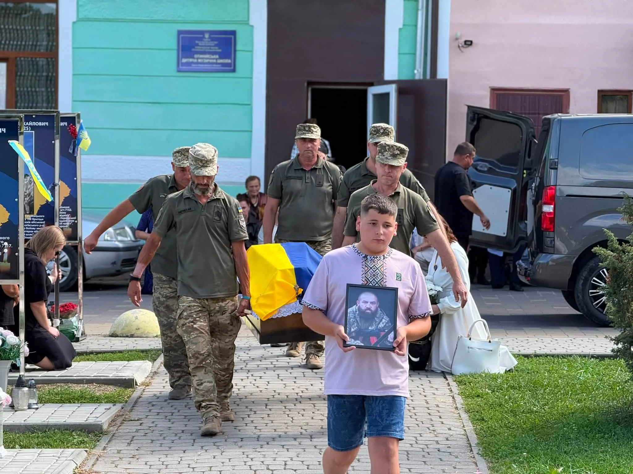 Хлопчик несе портрет загиблого воїна під час похорону