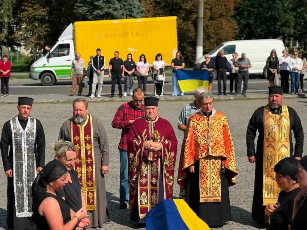Священники моляться на церемонії з українським прапором