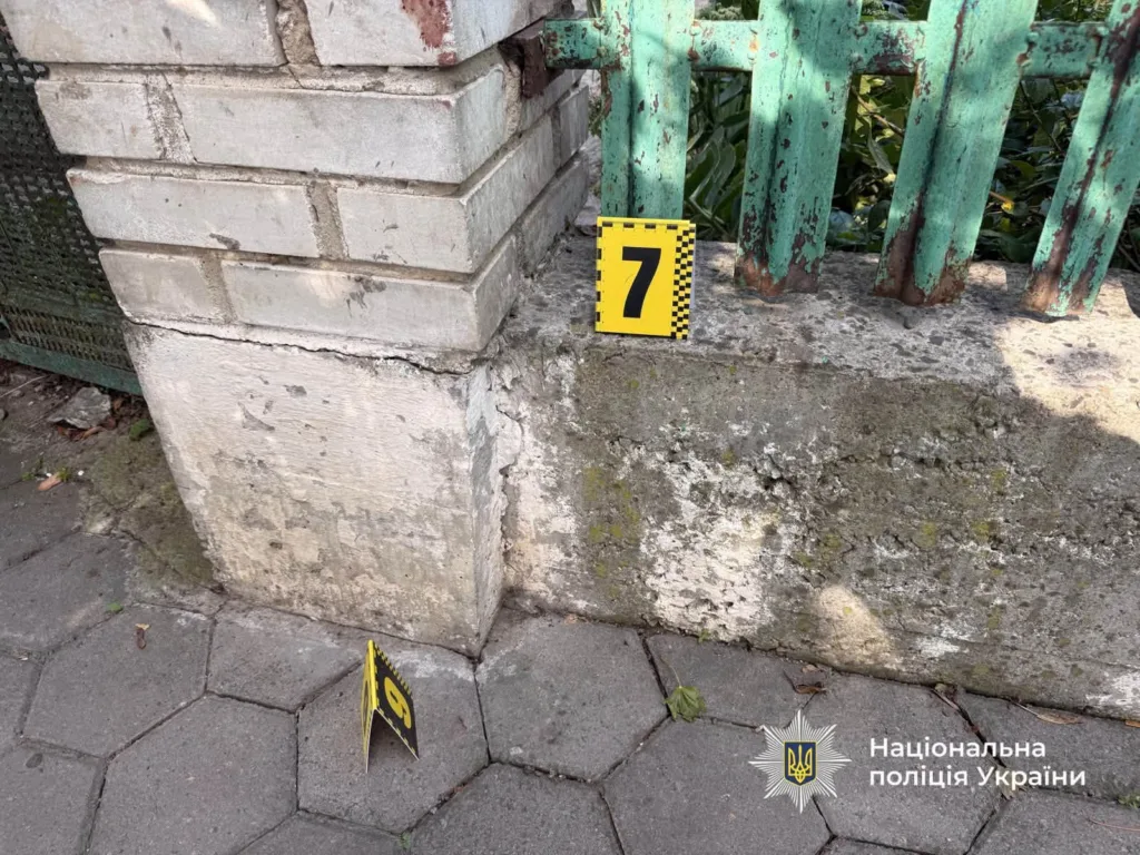 Поліцейська мітка біля пошкодженого паркану та цегляної опори