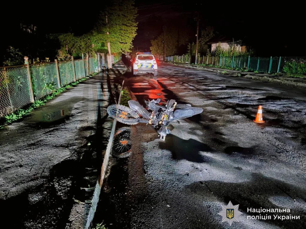 Пошкоджений мотоцикл біля поліцейського авто вночі