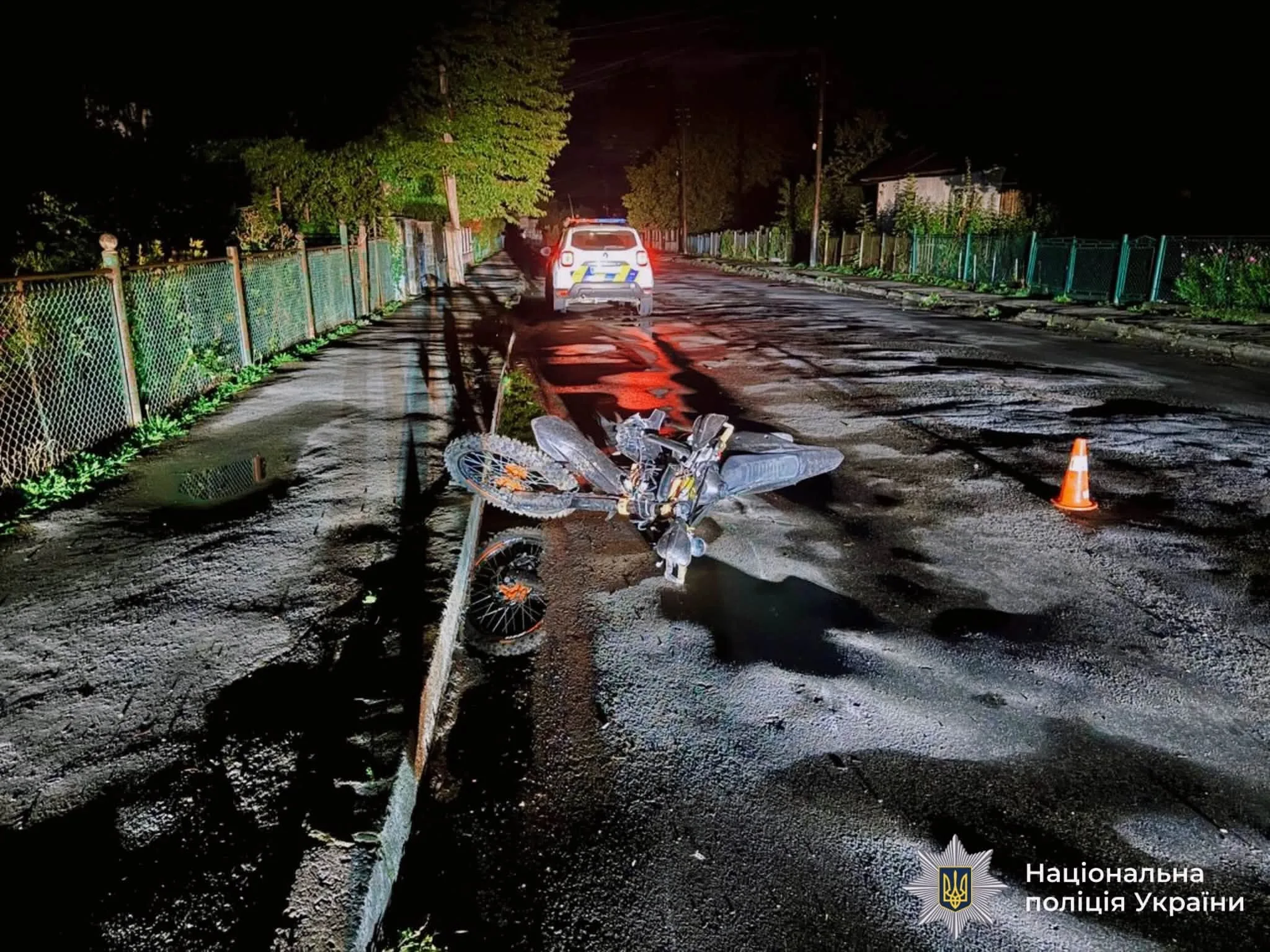 Пошкоджений мотоцикл біля поліцейського авто вночі