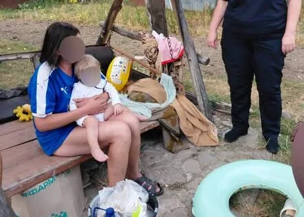 Жінка з дитиною сидить на лаві біля рятувального спорядження