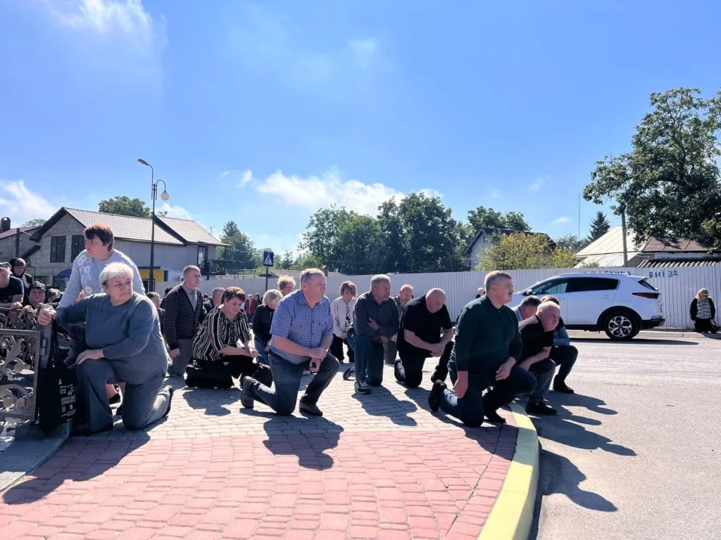Люди навколішки під час хвилини мовчання на вулиці
