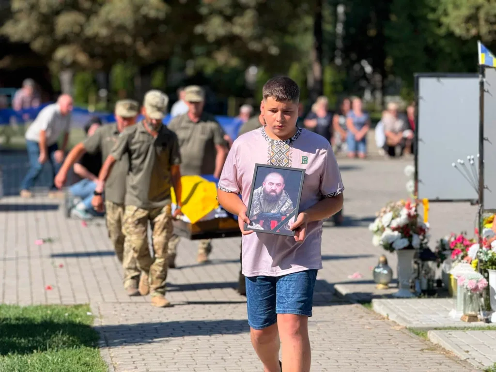 Хлопець несе портрет загиблого воїна на похороні