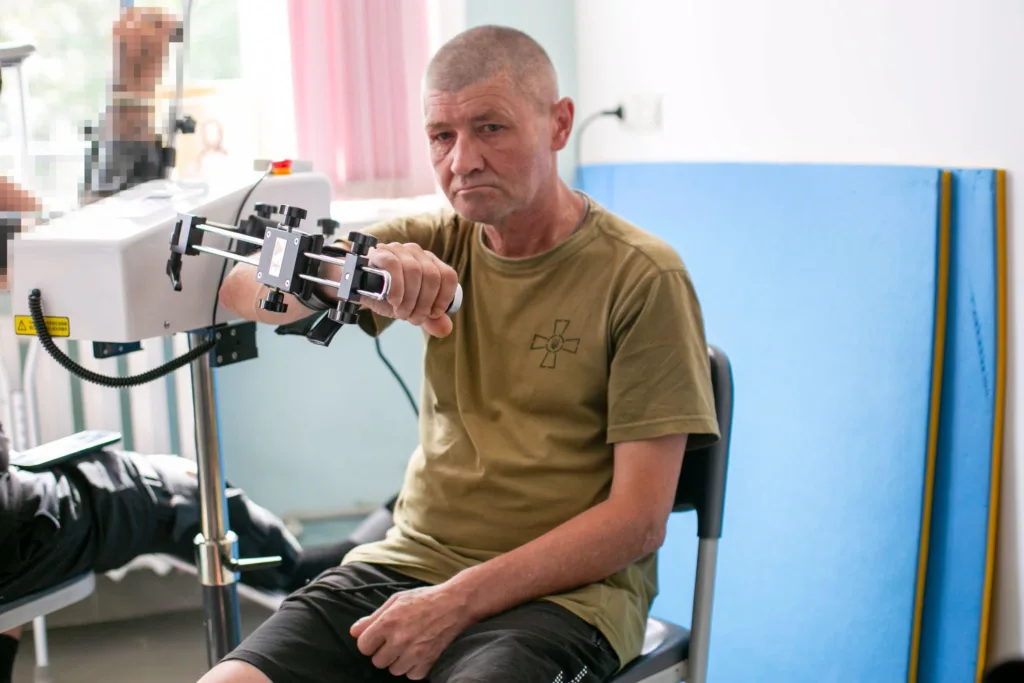 Чоловік виконує вправу для руки на реабілітаційному тренажері