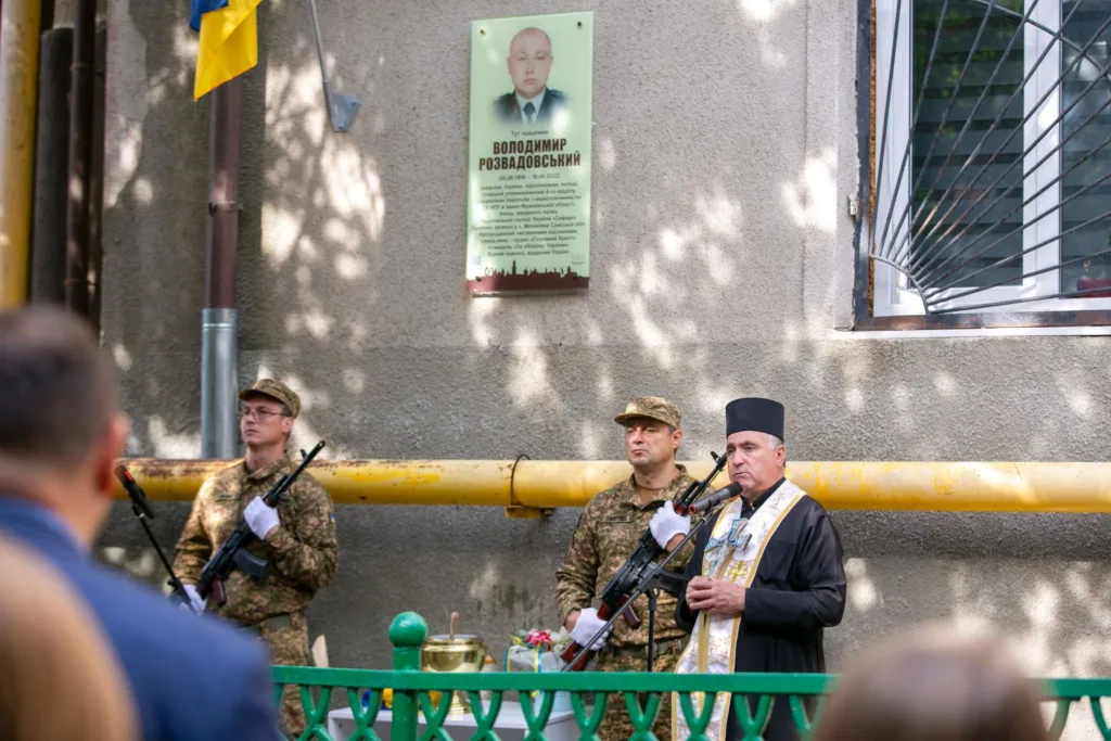 Священник освячує меморіальну дошку військовому