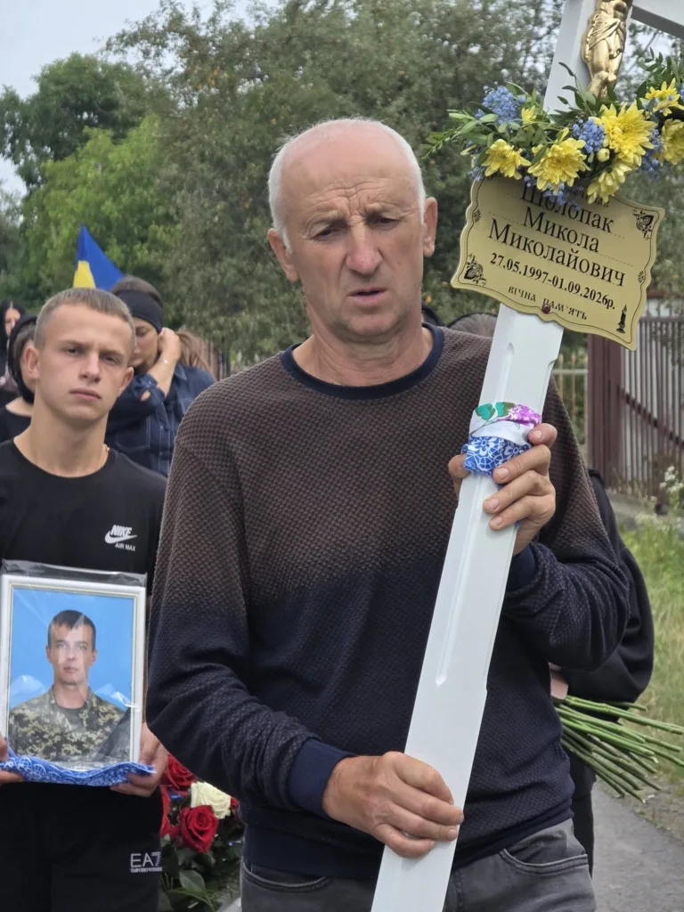 Чоловік несе хрест на похороні українського військового
