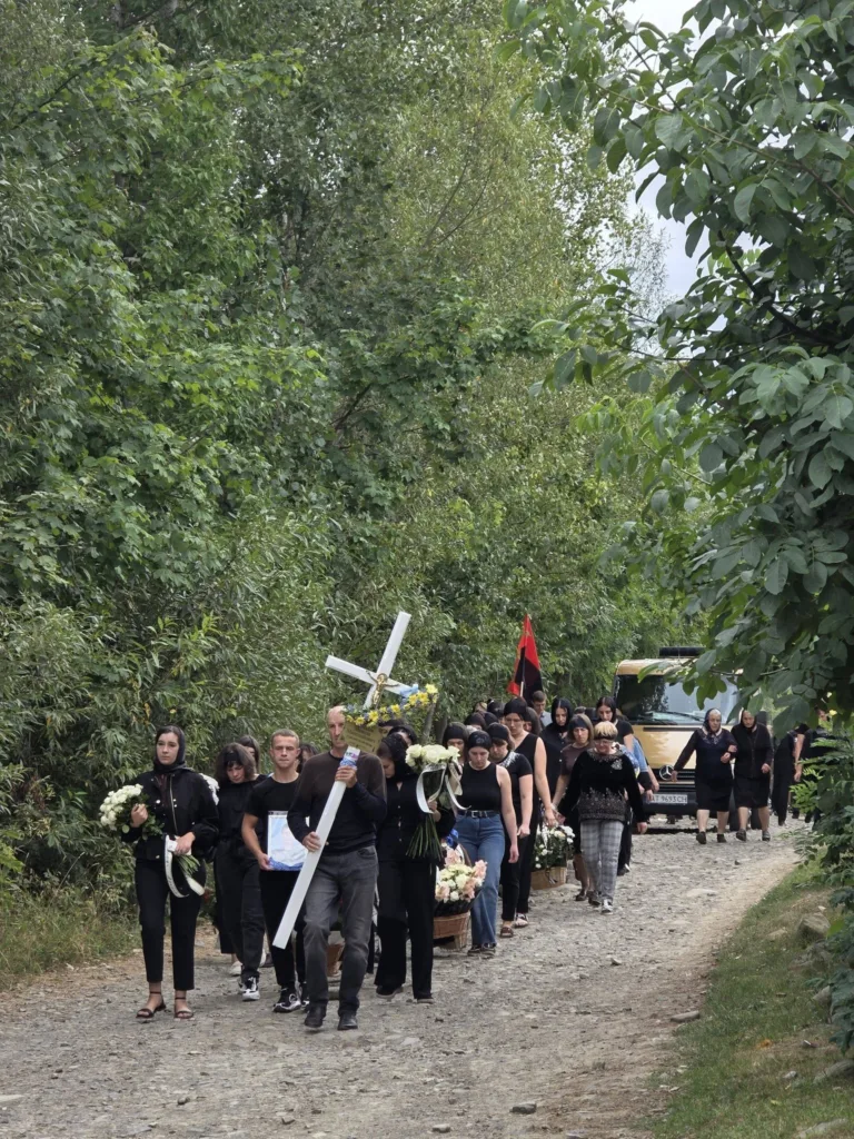 Жалобна процесія з хрестом і квітами лісовою дорогою