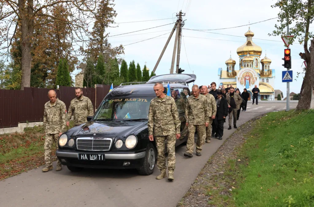 Військові супроводжують похоронний кортеж біля церкви