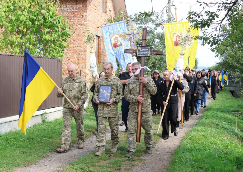 Похоронна процесія з військовими, хрестом і українським прапором