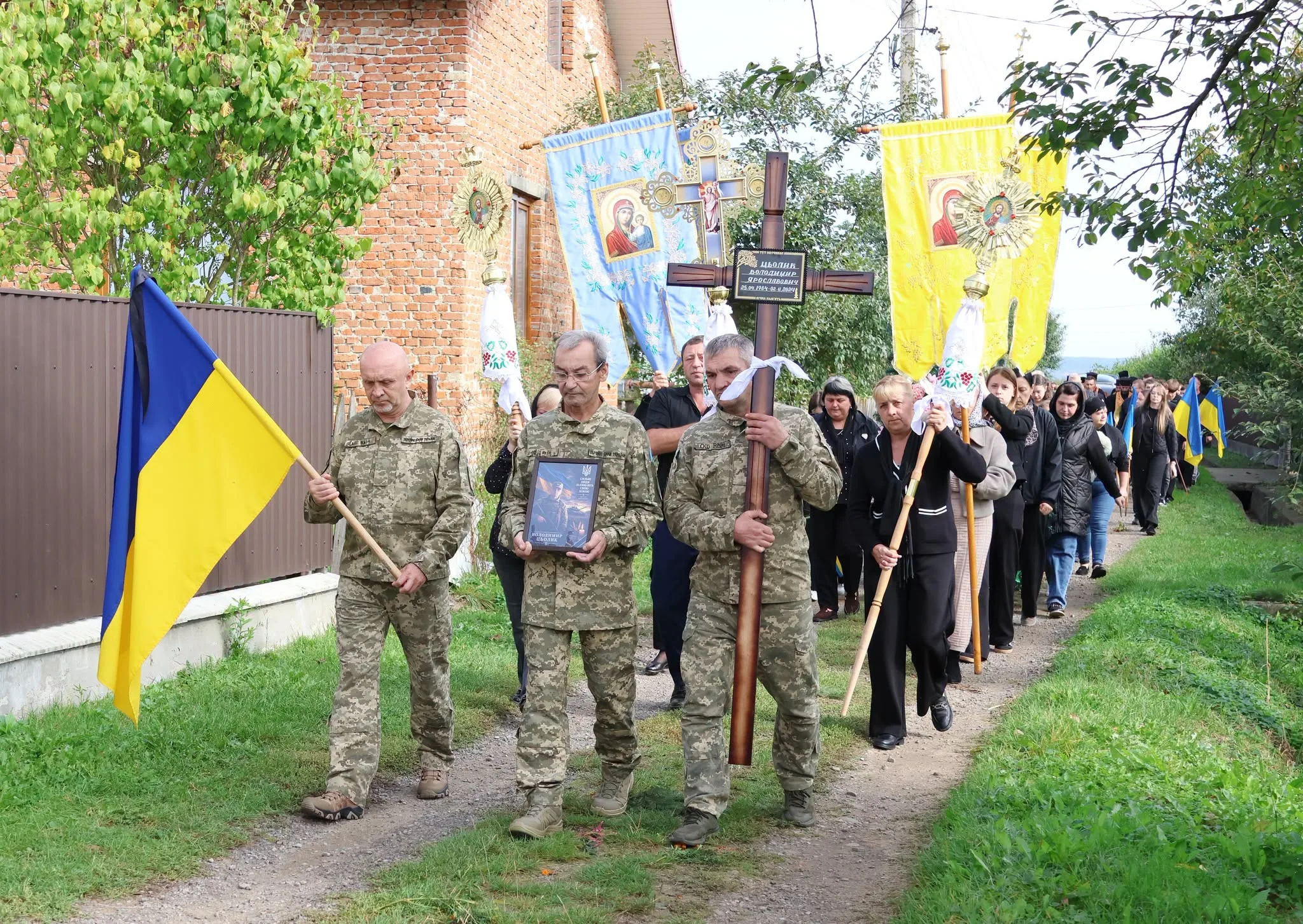 Похоронна процесія з військовими, хрестом і українським прапором