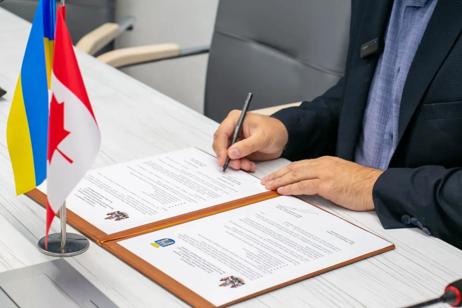 Посадовець підписує документи поруч із прапорами України та Грузії