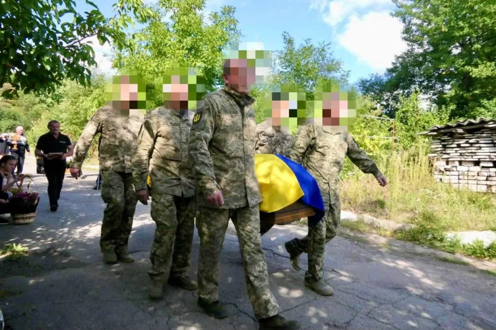 Військові несуть труну, накриту українським прапором