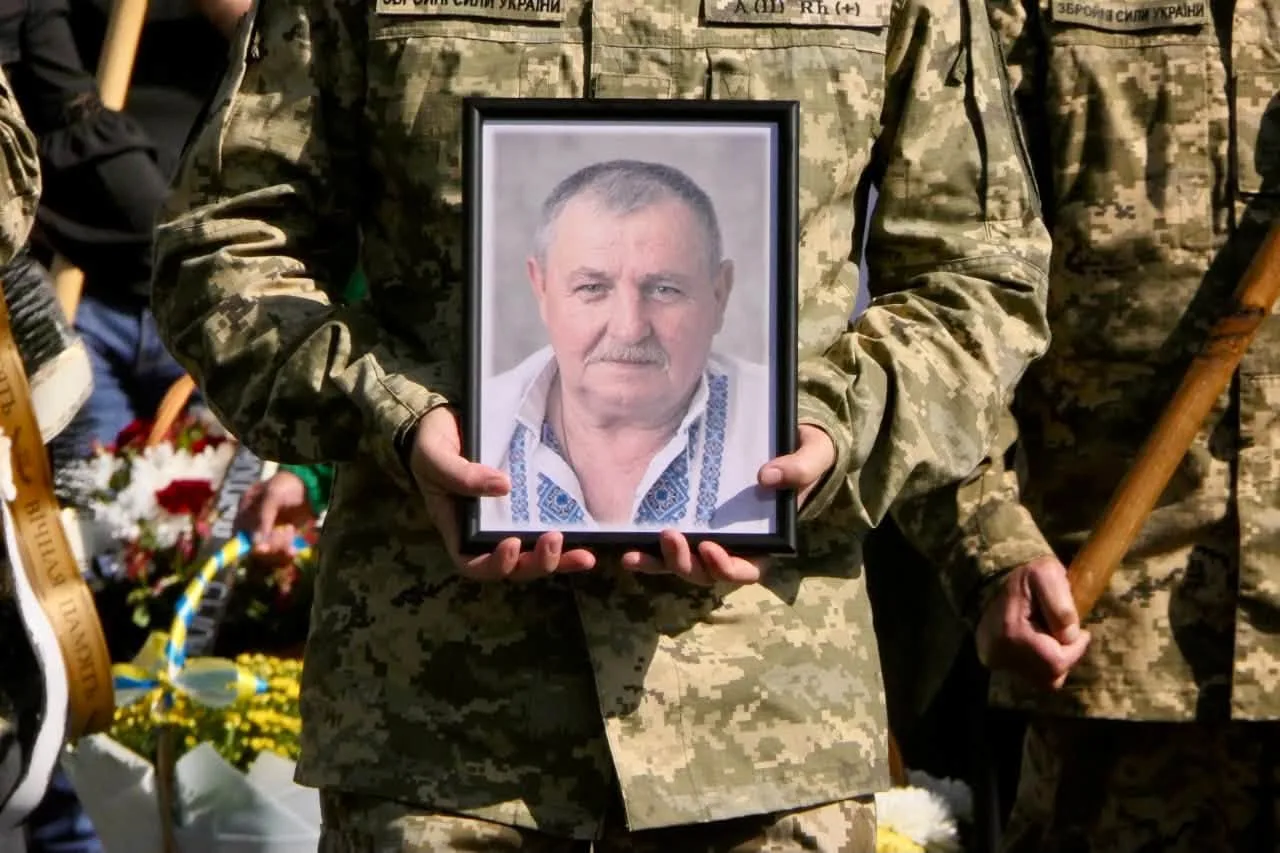 Військовий тримає портрет загиблого чоловіка на церемонії