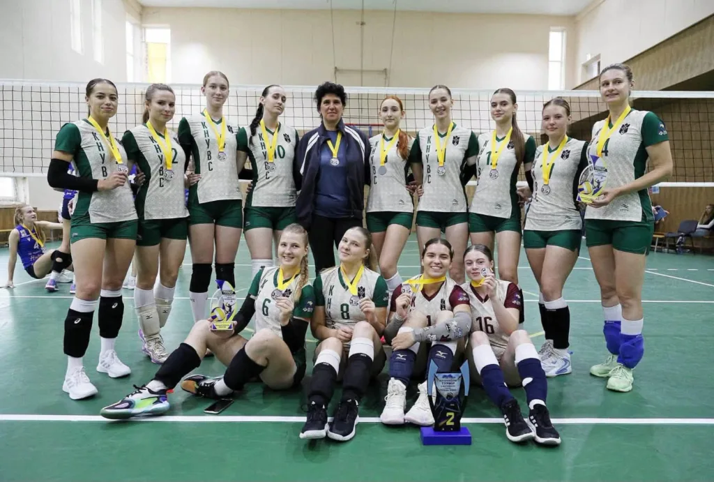 Волейбольна команда з медалями та кубками у спортзалі